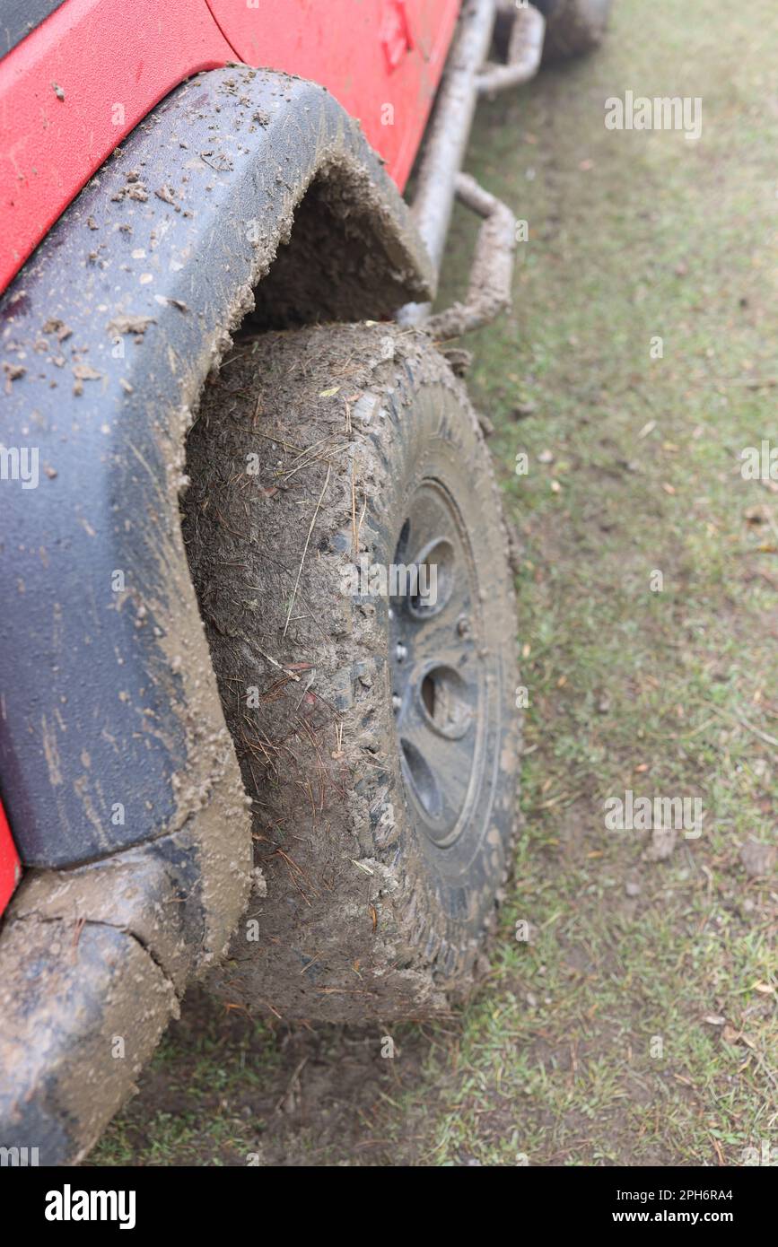 Offroad car wheel covered with wet dirt at countryside Stock Photo