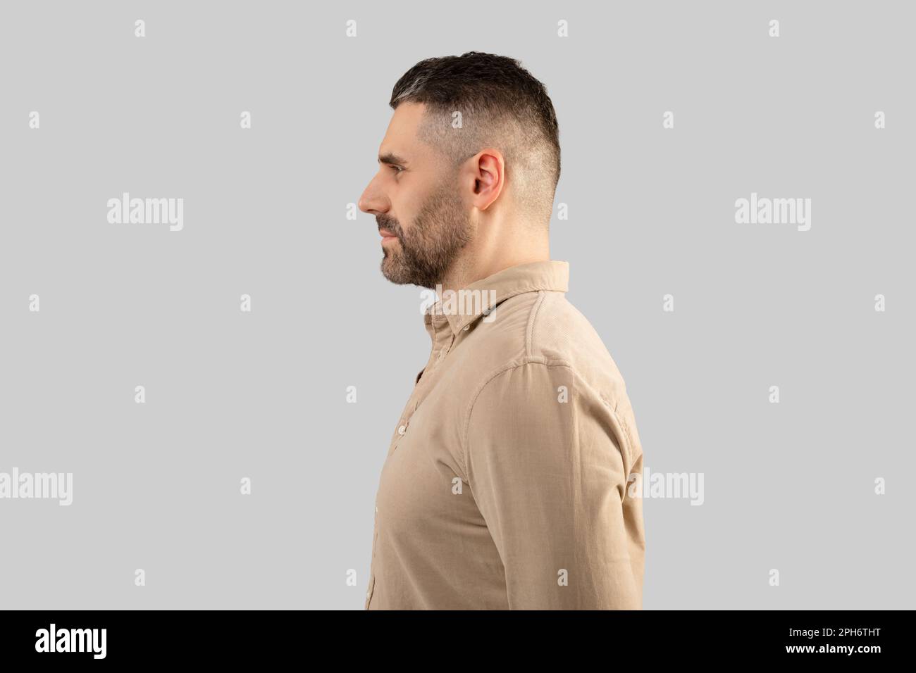 Profile portrait of bearded middle aged man in shirt, standing on light grey studio background, side view, free space Stock Photo
