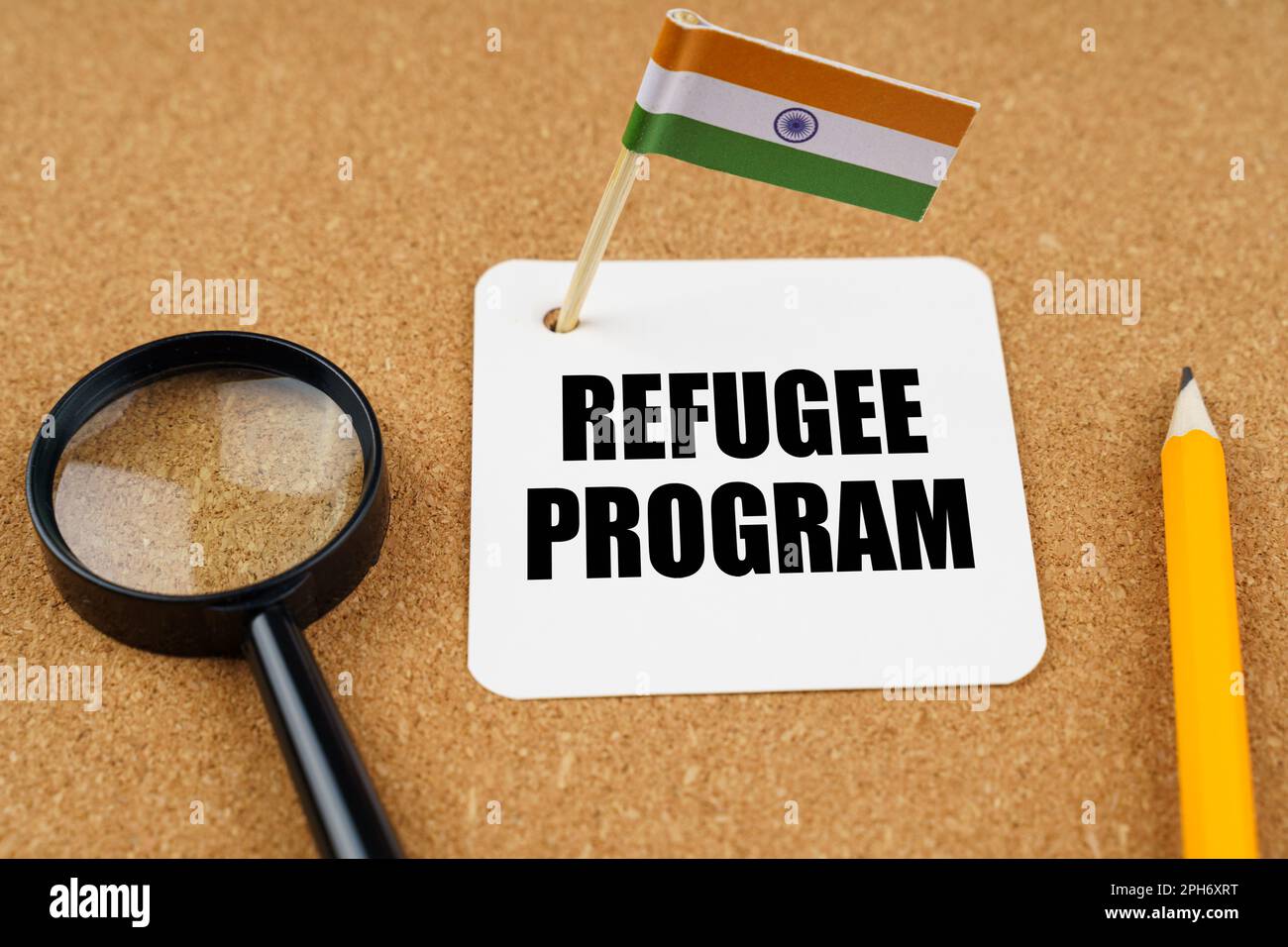 On the table is the flag of India, a pencil, a magnifying glass and a sheet of paper with the inscription - Refugee Program Stock Photo