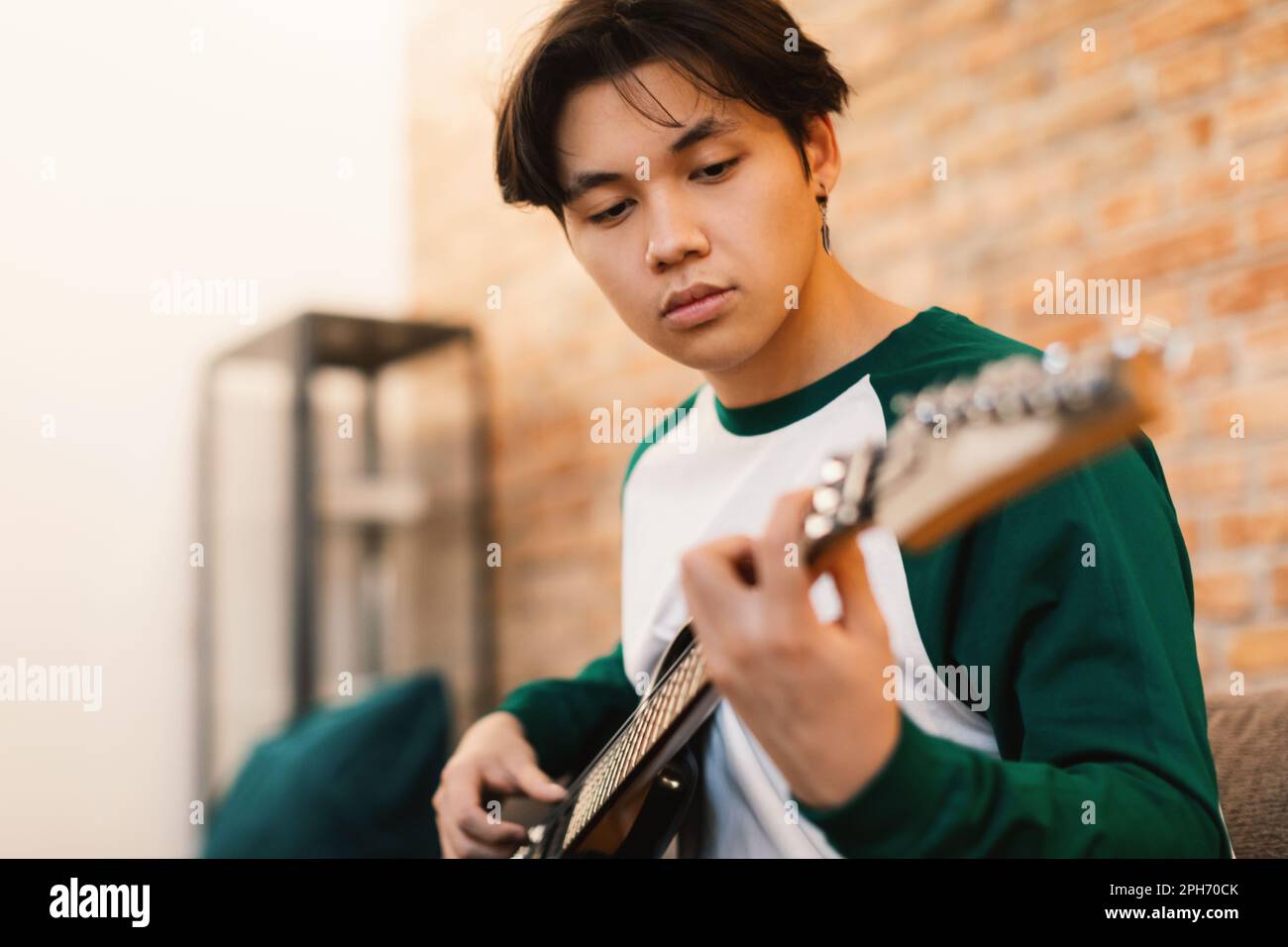 Japanese Teen Guy Playing Electric Guitar Taking Chords At Home Stock
