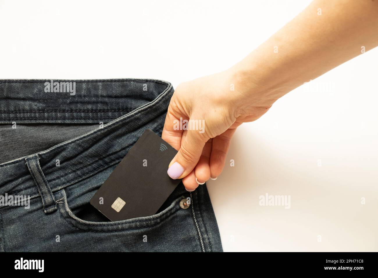 A woman's hand takes out a bank card from a jeans pocket, money Stock Photo