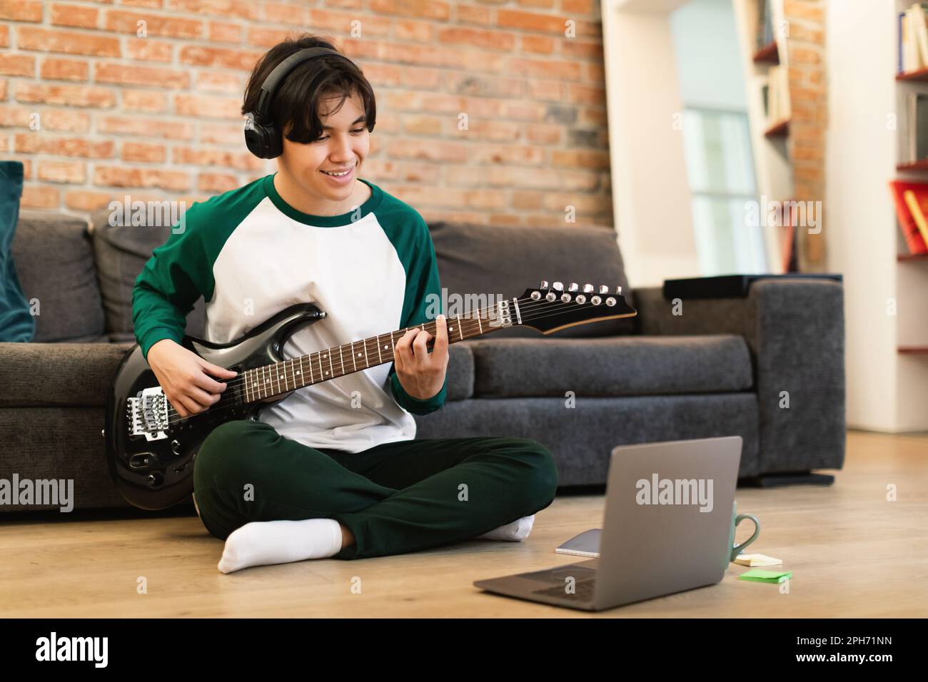Asian Guy Playing Music On Electric Guitar Near Laptop Indoor Stock