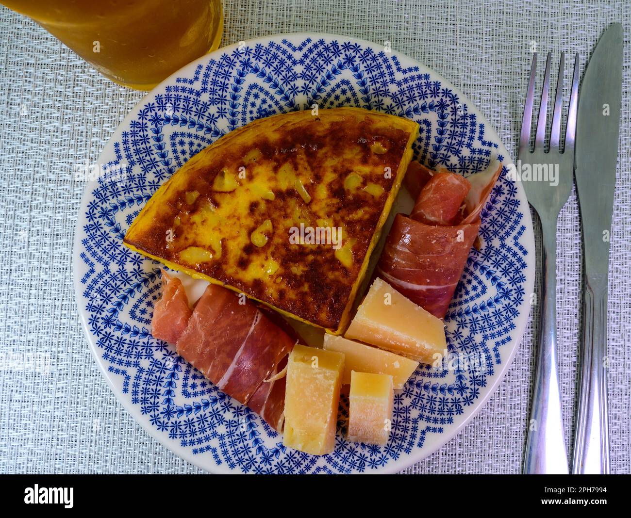 Spanish food, portion of potato omelette tortilla de patatas with onion served with cheese and jamon in cafe Stock Photo