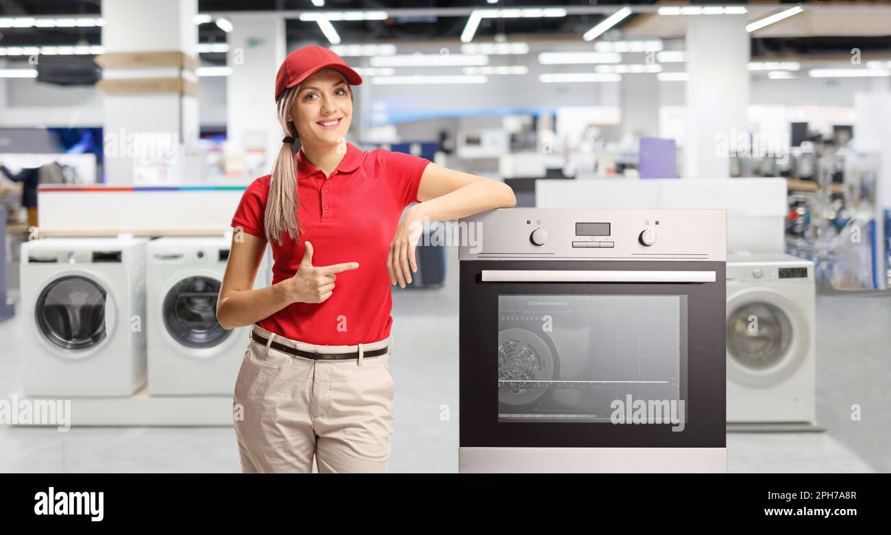 Female shop assistant pointing at an electrcal oven inside a store Stock Photo