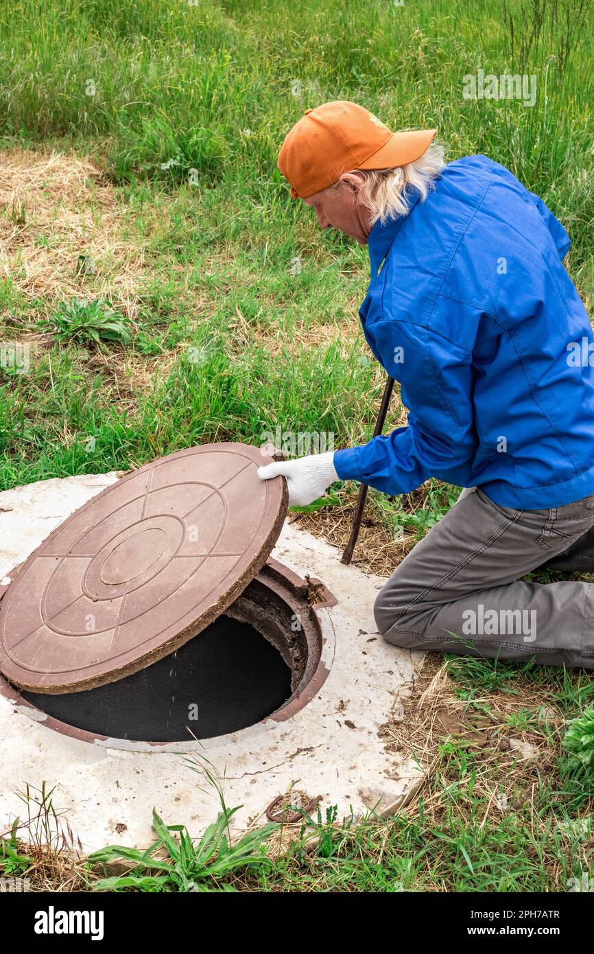 the man opened the cover of the sewer manhole to pump out the sewage
