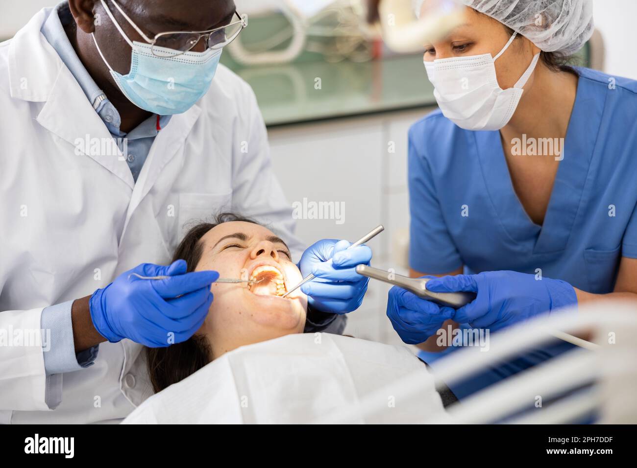 Dentist and nurse performing tooth enamel restoration operation on