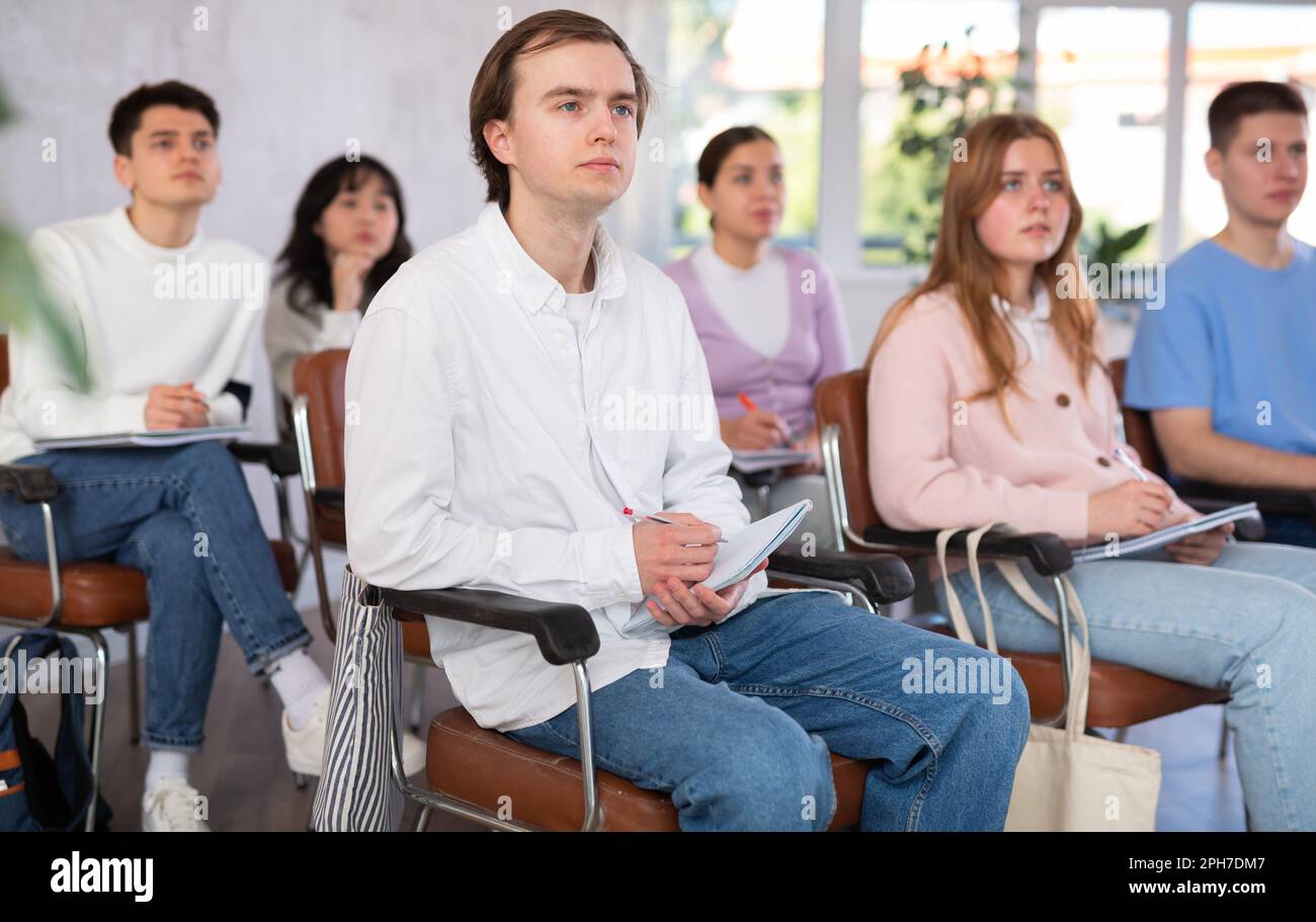 Young male student listening attentively to lecture in lecture hall Stock Photo