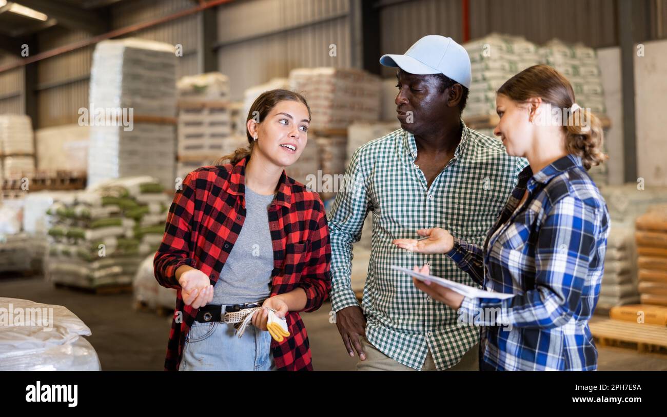 Workers and manager discussing completed work in large warehouse Stock Photo