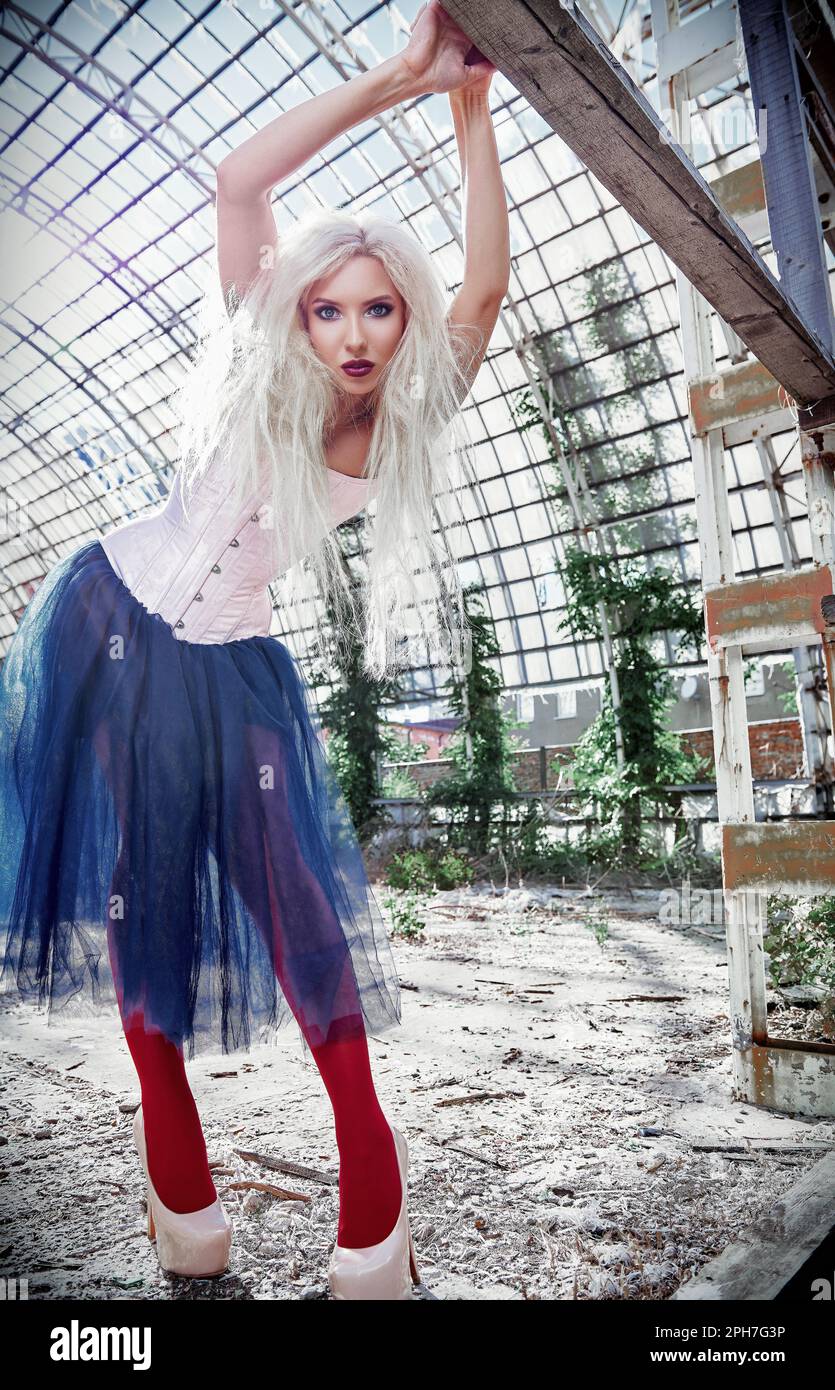 Portrait of the beautiful freak girl. Attractive strange woman wearing colorful corset, tights and tutu skirt in abandoned place. Weird fashion Stock Photo