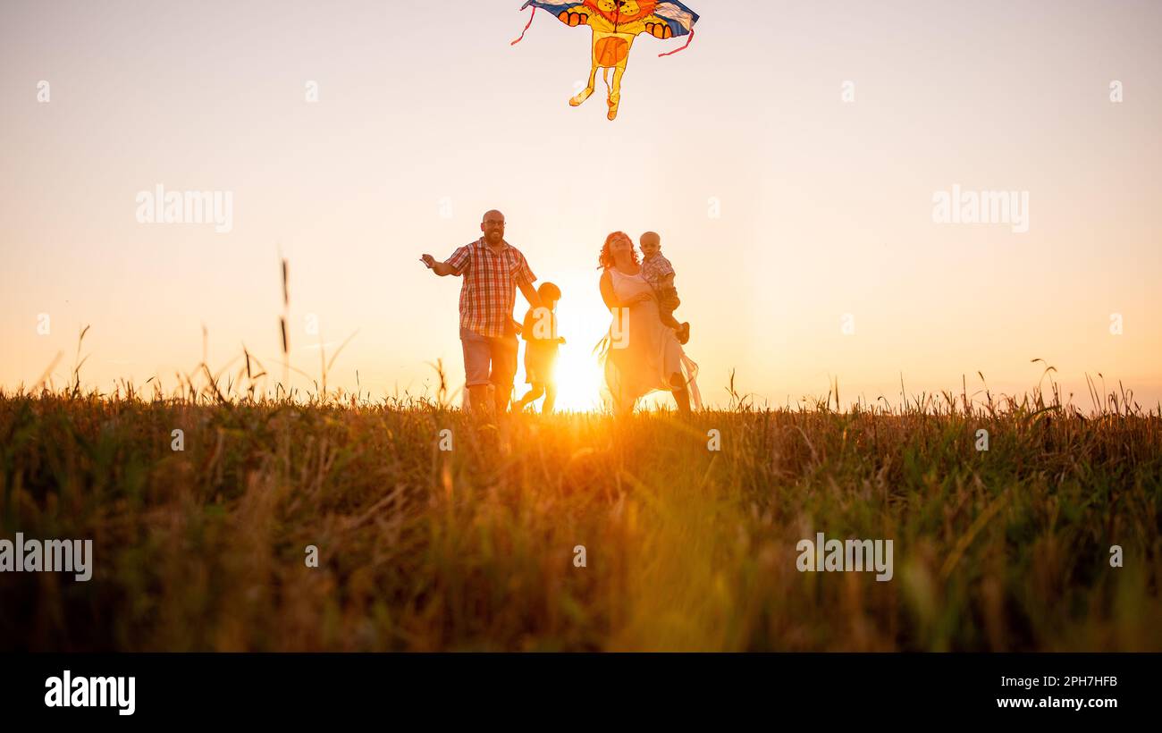 Panoramic diversity view of family running at sunset with kite in the ...