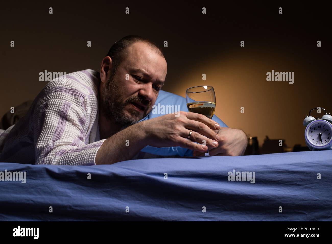 A man alone with a glass of wine in bed. Alcoholism, loneliness. Drink