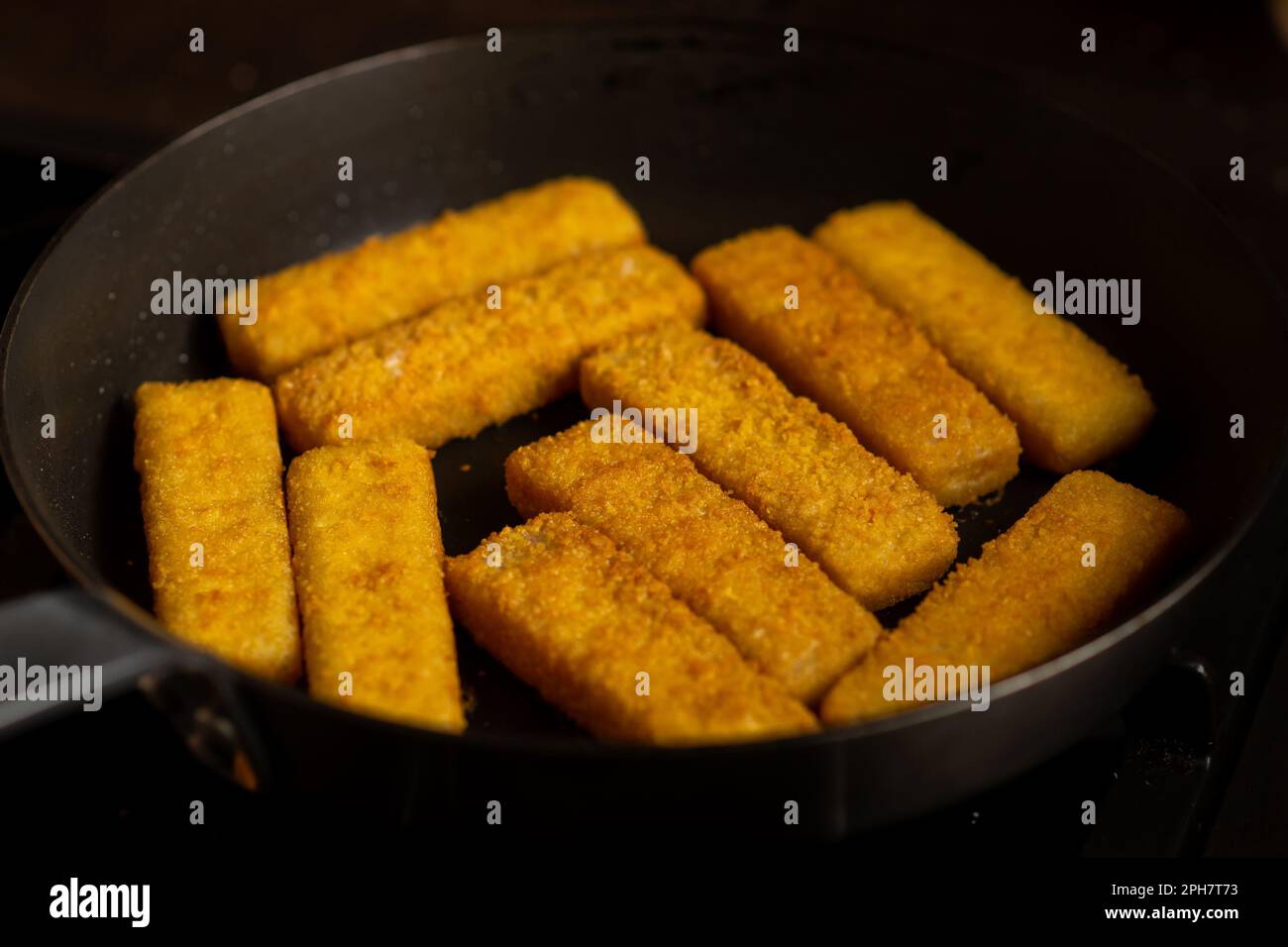 Breaded fish sticks in a frying pan. Preparation of frozen fish sticks