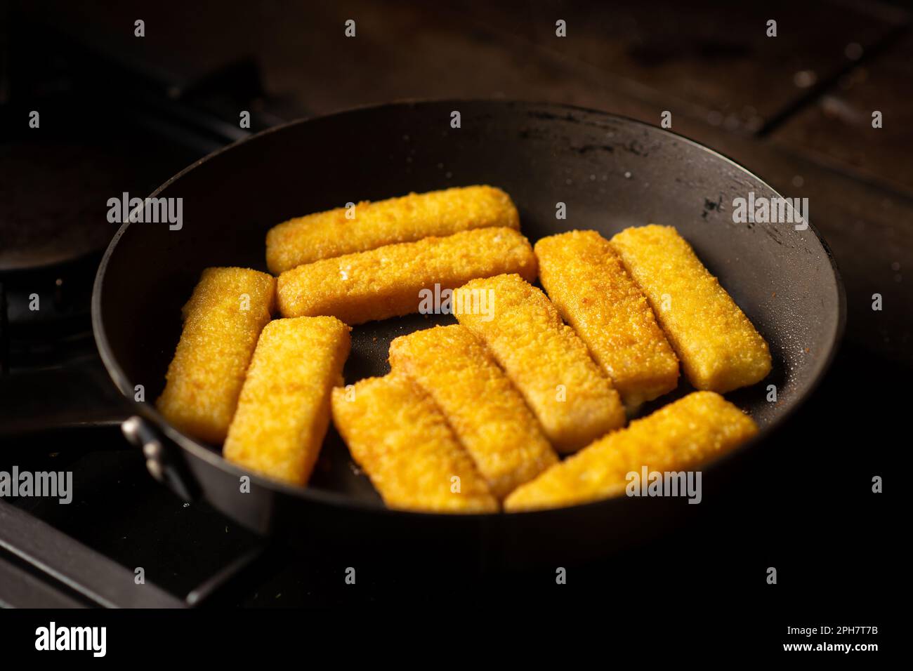 Breaded fish sticks in a frying pan. Preparation of frozen fish sticks