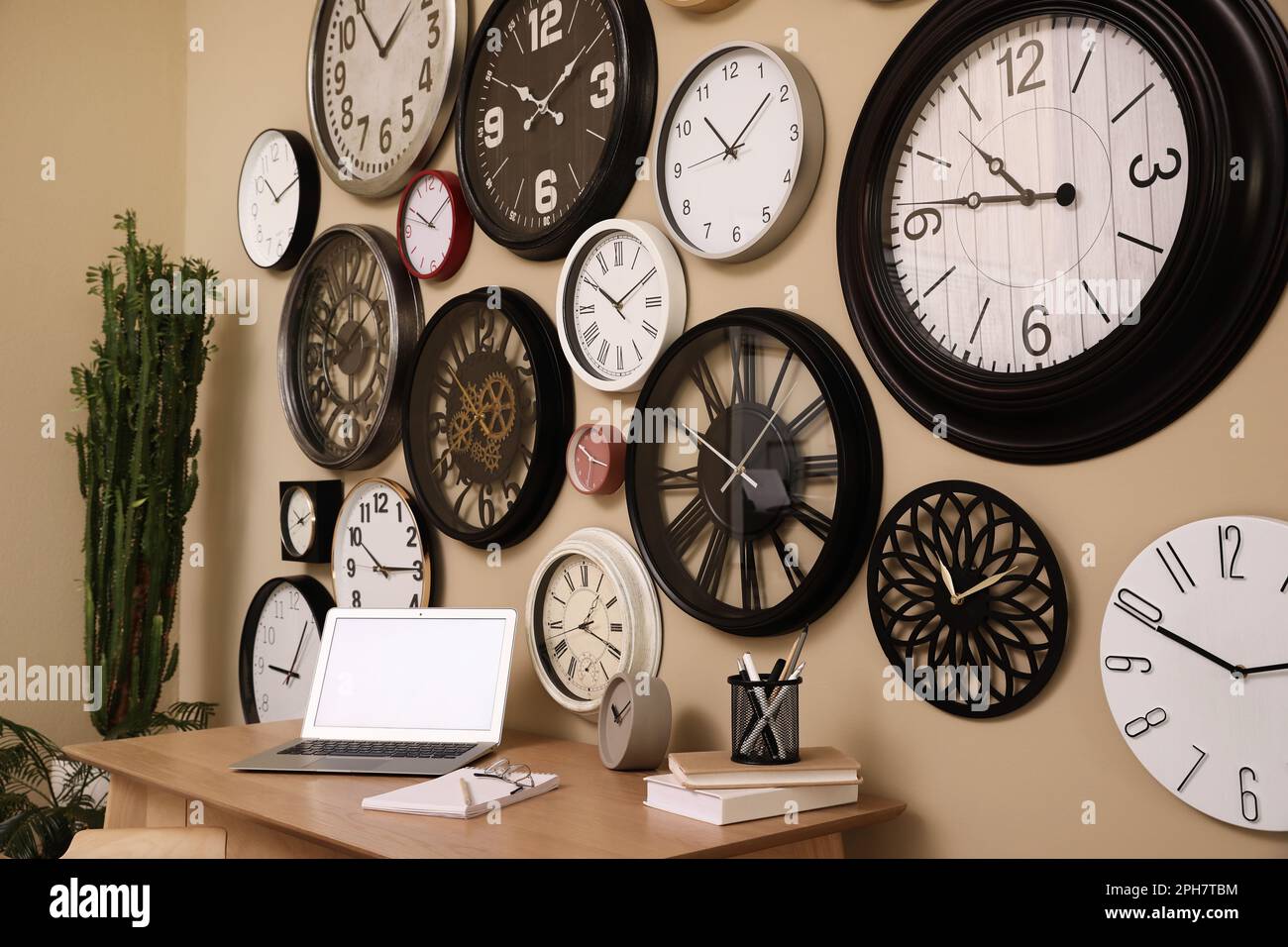 Stylish room interior with collection of wall clocks and workplace