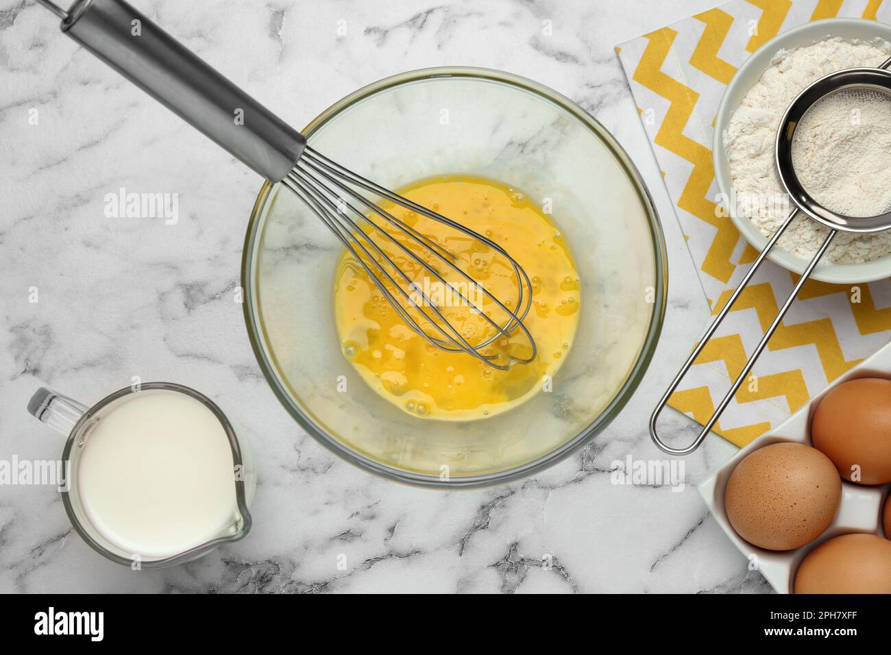 Whisked eggs and other ingredients on white marble table, flat lay