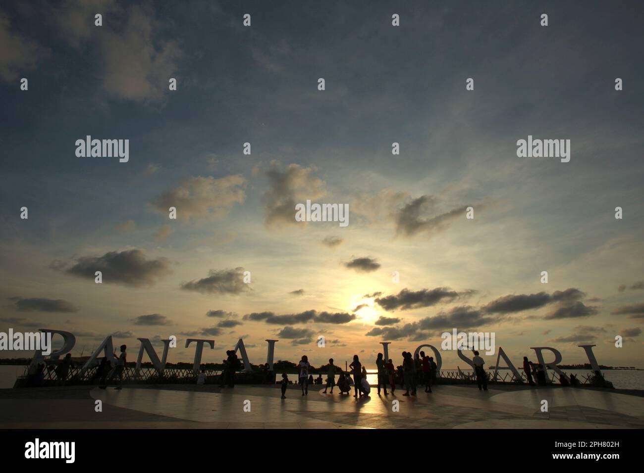 View of afternoon sky and people having leisure time on the beach platform of Losari in Makassar, a coastal city that is surrounded by controversies over coastal development and coastal resources management in South Sulawesi, Indonesia. Restoration or protection of coastal ecosystems is an important climate change adaptation action with multiple benefits, with bounded global mitigation benefits, according to the 2023 report published by the Intergovernmental Panel on Climate Change (IPCC), entitled 'Climate Change 2022: Impacts, Adaptation and Vulnerability'. Stock Photo