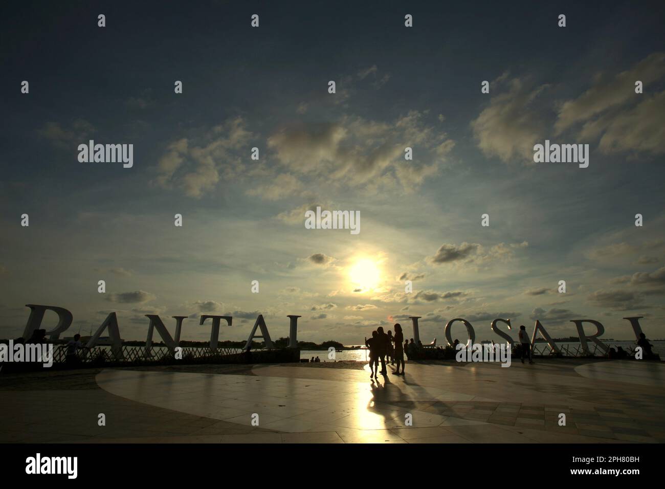 View of afternoon sky and people having leisure time on the beach platform of Losari in Makassar, a coastal city that is surrounded by controversies over coastal development and coastal resources management in South Sulawesi, Indonesia. Restoration or protection of coastal ecosystems is an important climate change adaptation action with multiple benefits, with bounded global mitigation benefits, according to the 2023 report published by the Intergovernmental Panel on Climate Change (IPCC), entitled 'Climate Change 2022: Impacts, Adaptation and Vulnerability'. Stock Photo