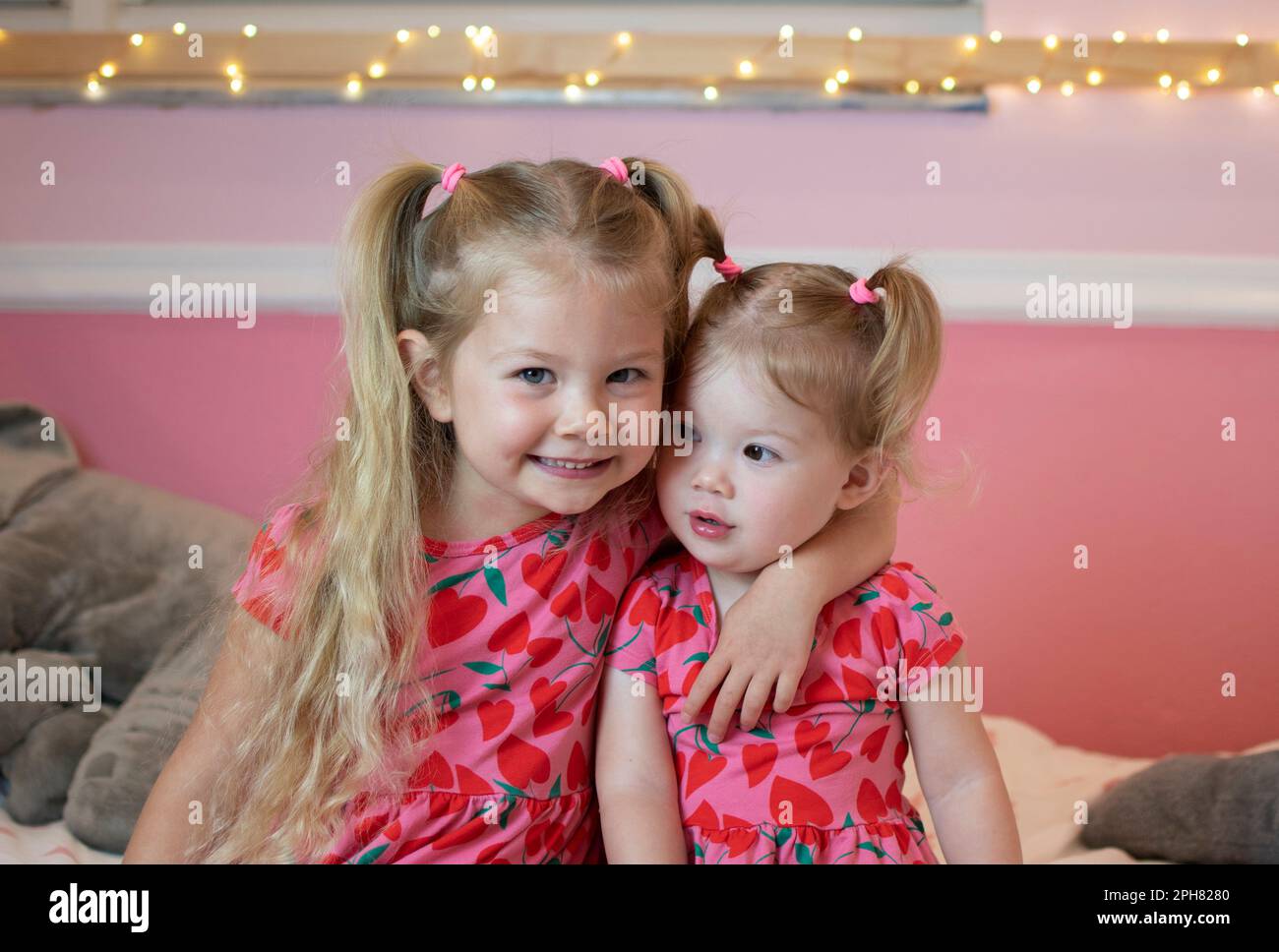 Two caucasian sisters in matching clothes hugging. Sister's love