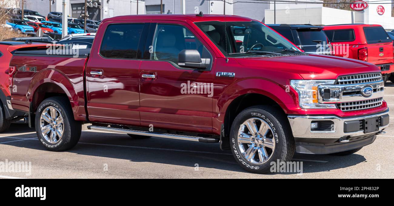 A red Ford F150 four door pickup truck for sale at a dealership in