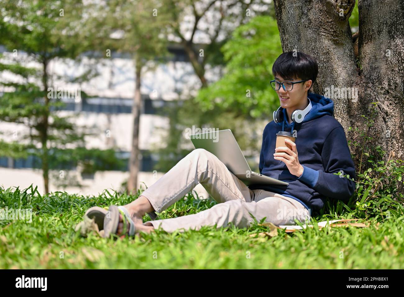 Happy young Asian male college student using his laptop to manage his ...