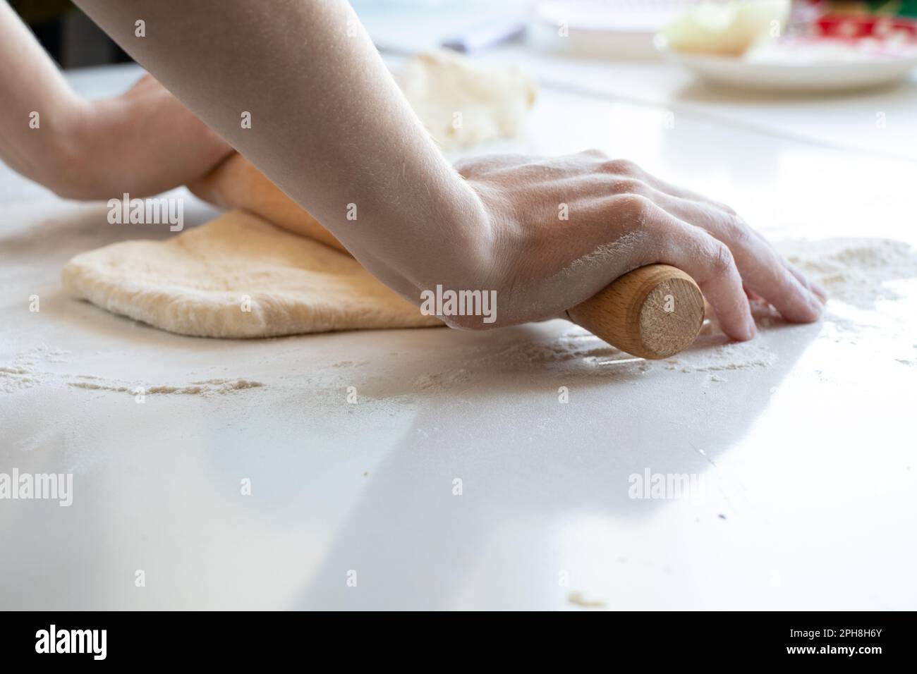 female hands knead raw dough on a white table in the kitchen, dough Stock Photo