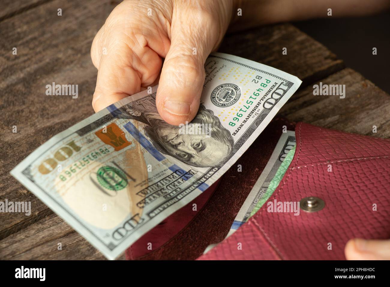 hands of an old woman on american dollars on a wooden table close up Stock Photo
