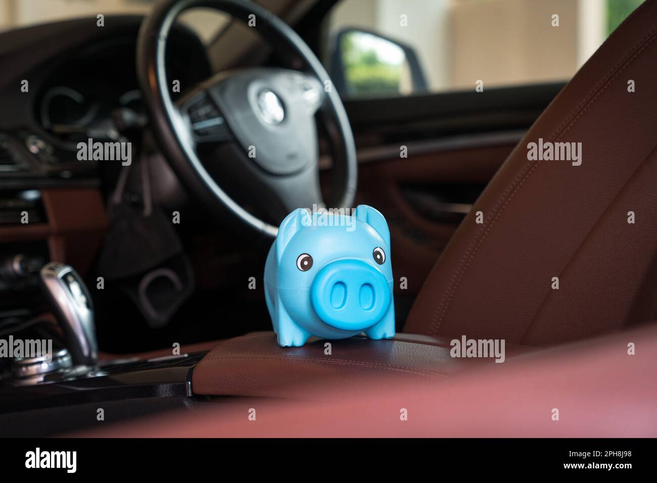 Blue piggy bank money box Inside a car vehicle. Car purchase and insurance concept. Stock Photo