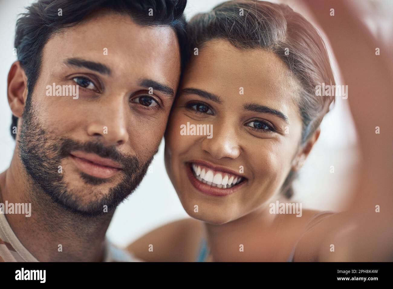 We believe in a thing called love. Portrait of a happy young couple posing for a selfie on their couch at home. Stock Photo