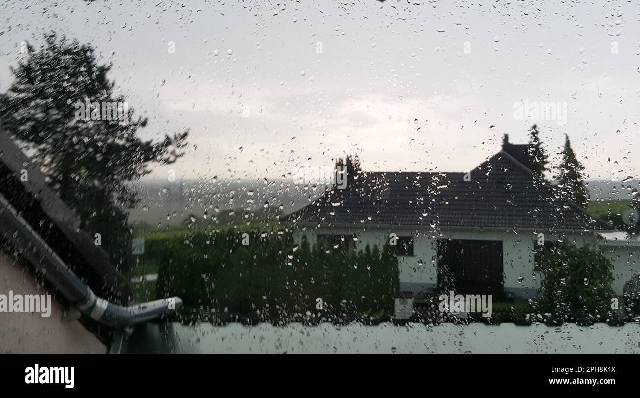 A window with rain droplets condensing on the glass, looking out onto ...
