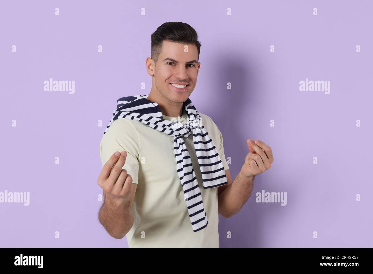 Handsome man snapping fingers on violet background Stock Photo