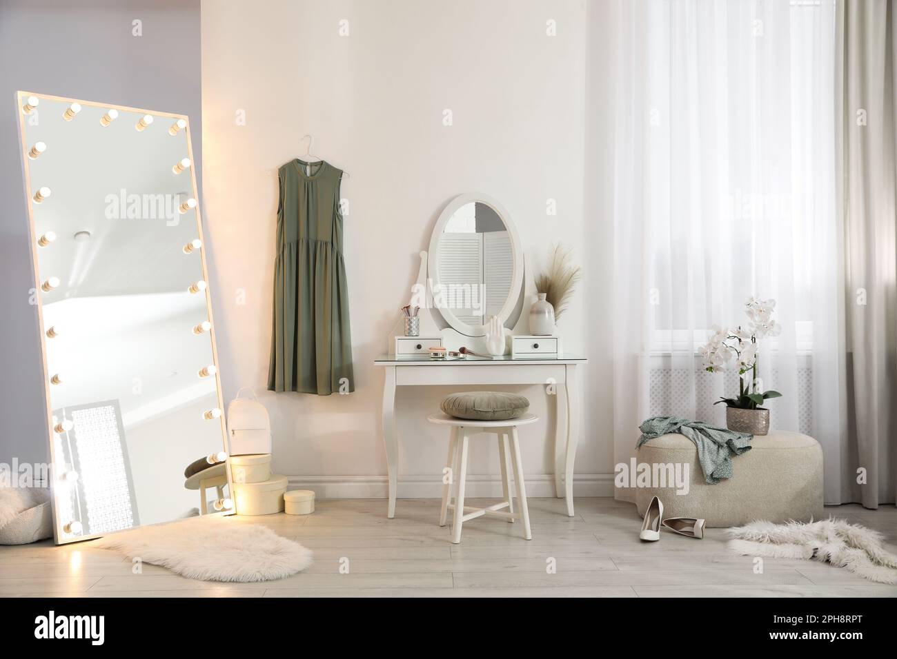 Large mirror with light bulbs and dressing table in stylish room