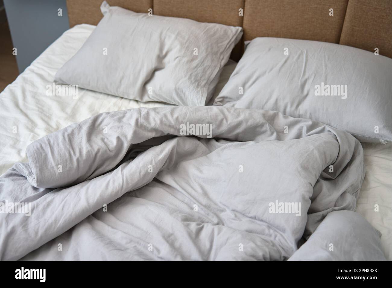 Unmade bed after sleeping. Crumpled bed with pillows, blanket and