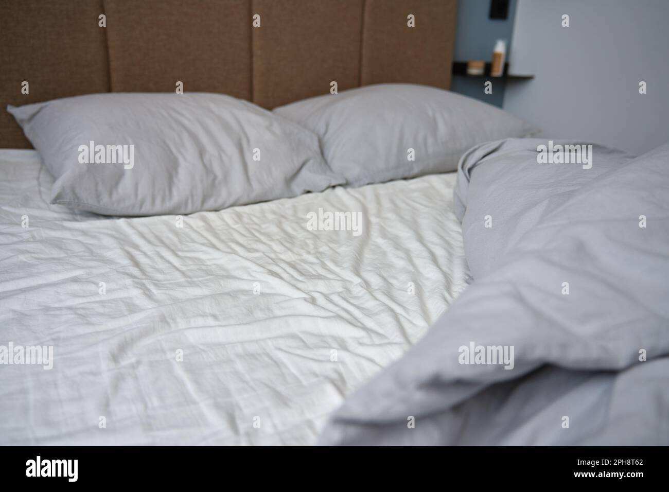 Unmade bed after sleeping. Crumpled bed with pillows, blanket and