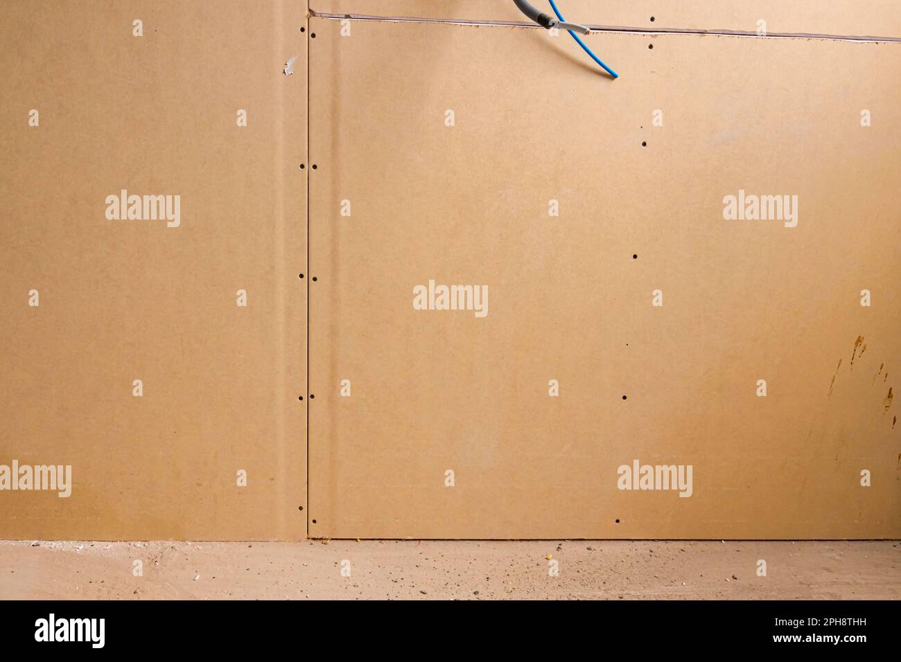 Brown gypsum boards installed on the partition wall of building under construction at the
