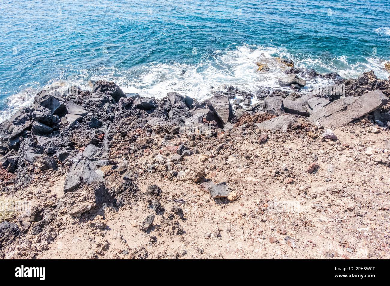 Wct Rocks crystal clear sea caresses the dark rocks of the coast of the island of ...
