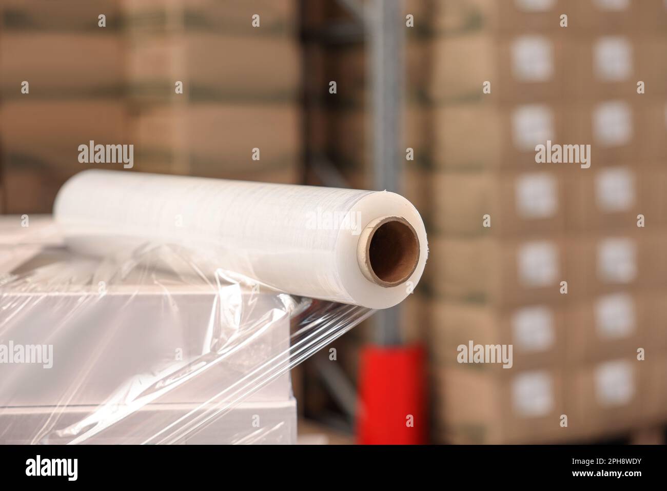Roll of stretch wrap on box in warehouse, space for text Stock Photo