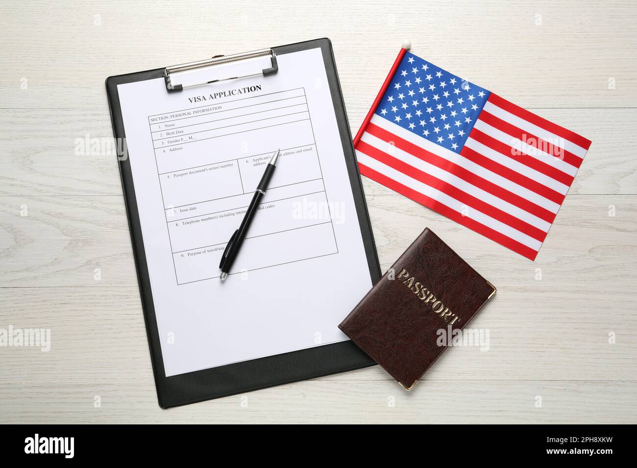 American flag, visa application form and passport on white wooden table, flat lay Stock Photo