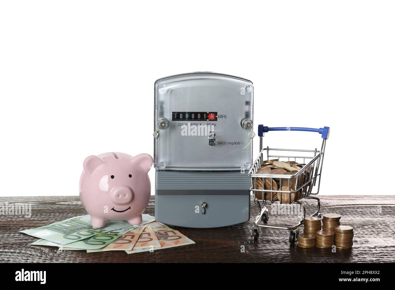 Electricity meter, piggy bank and small shopping cart with money on ...