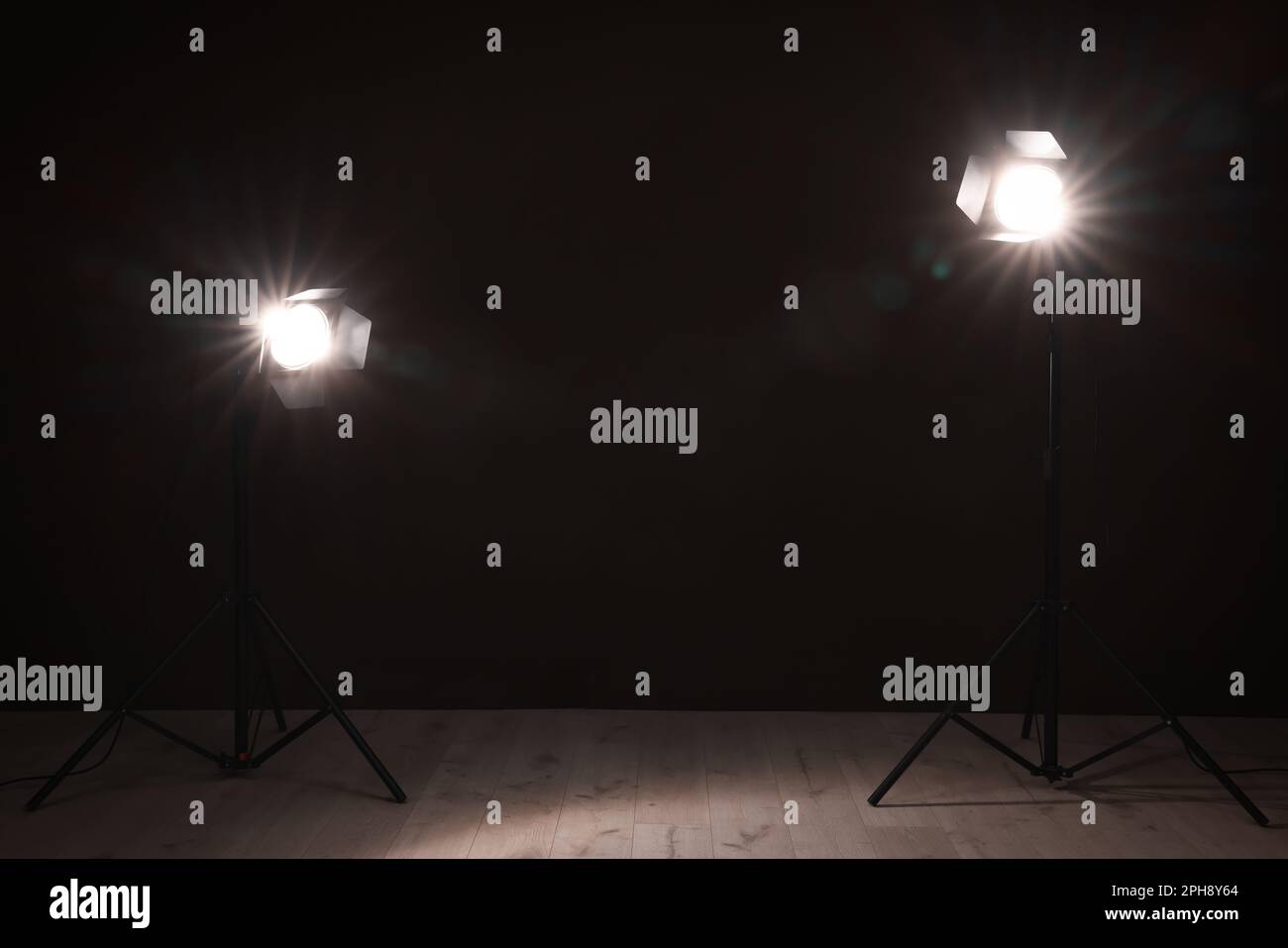 Bright spotlights near wall in dark room, space for text Stock Photo