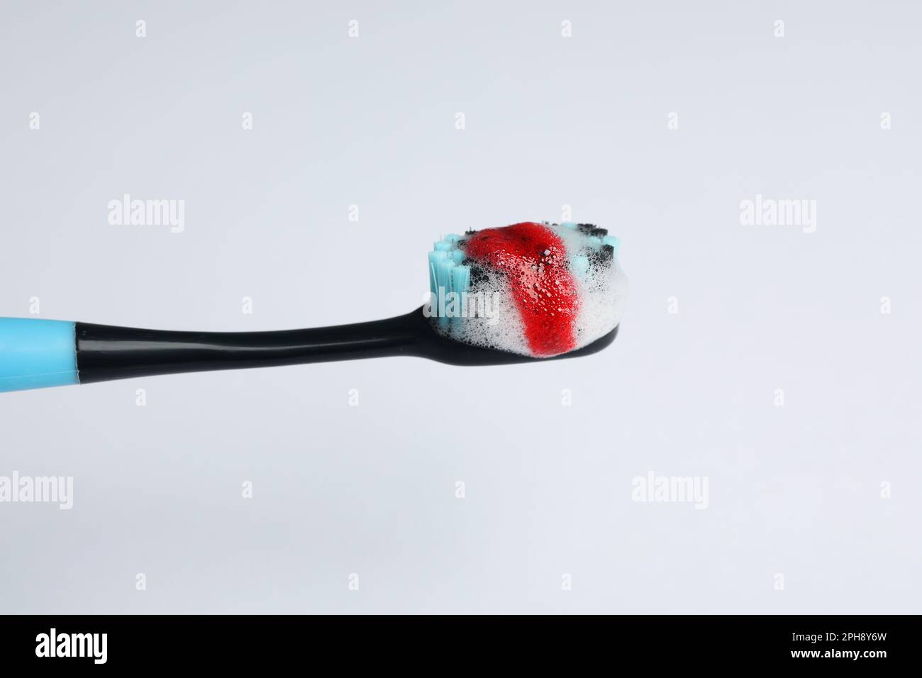 Toothbrush with paste and blood on white background, closeup. Gum