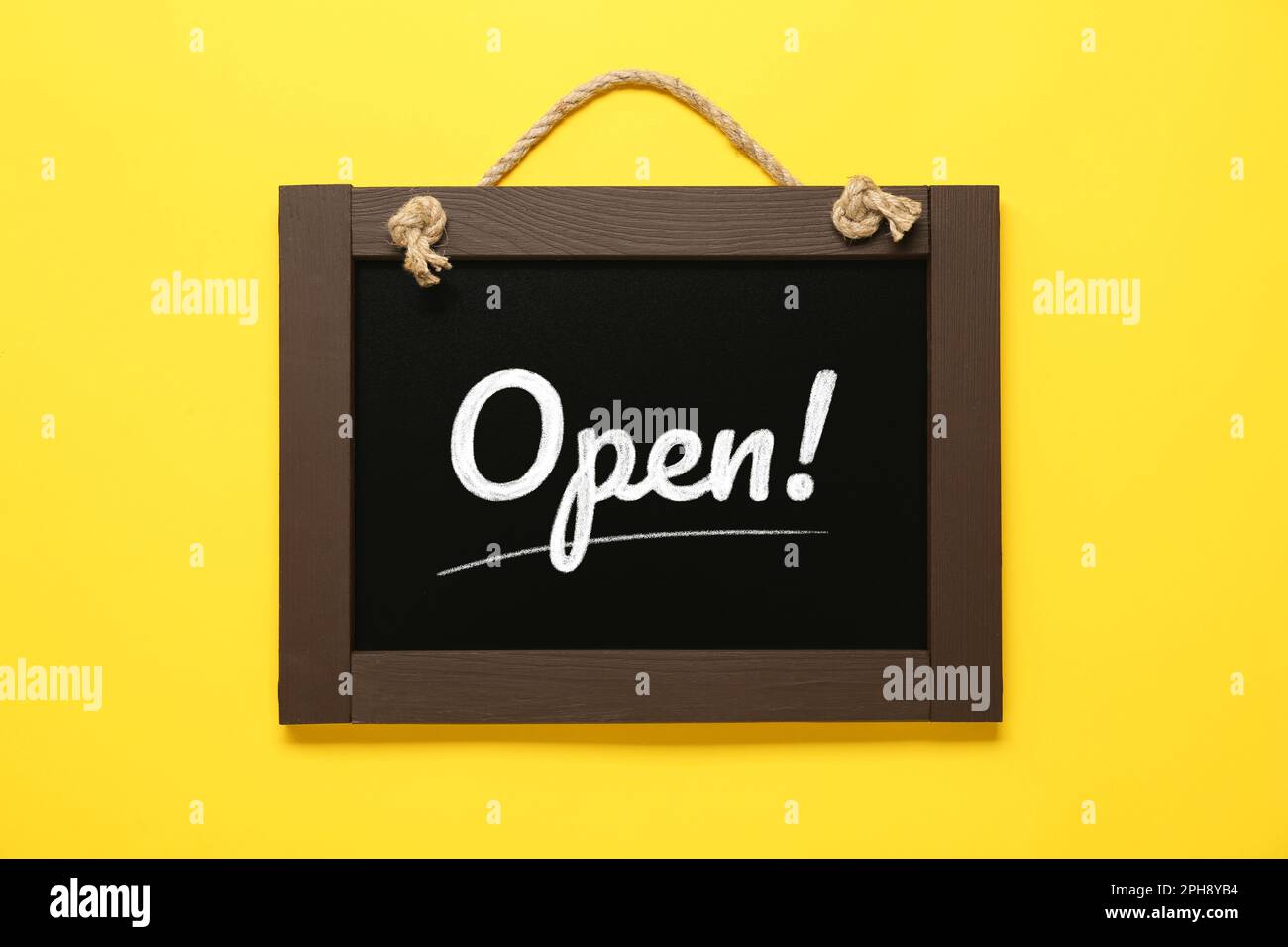 Small chalk board with word Open on yellow background Stock Photo