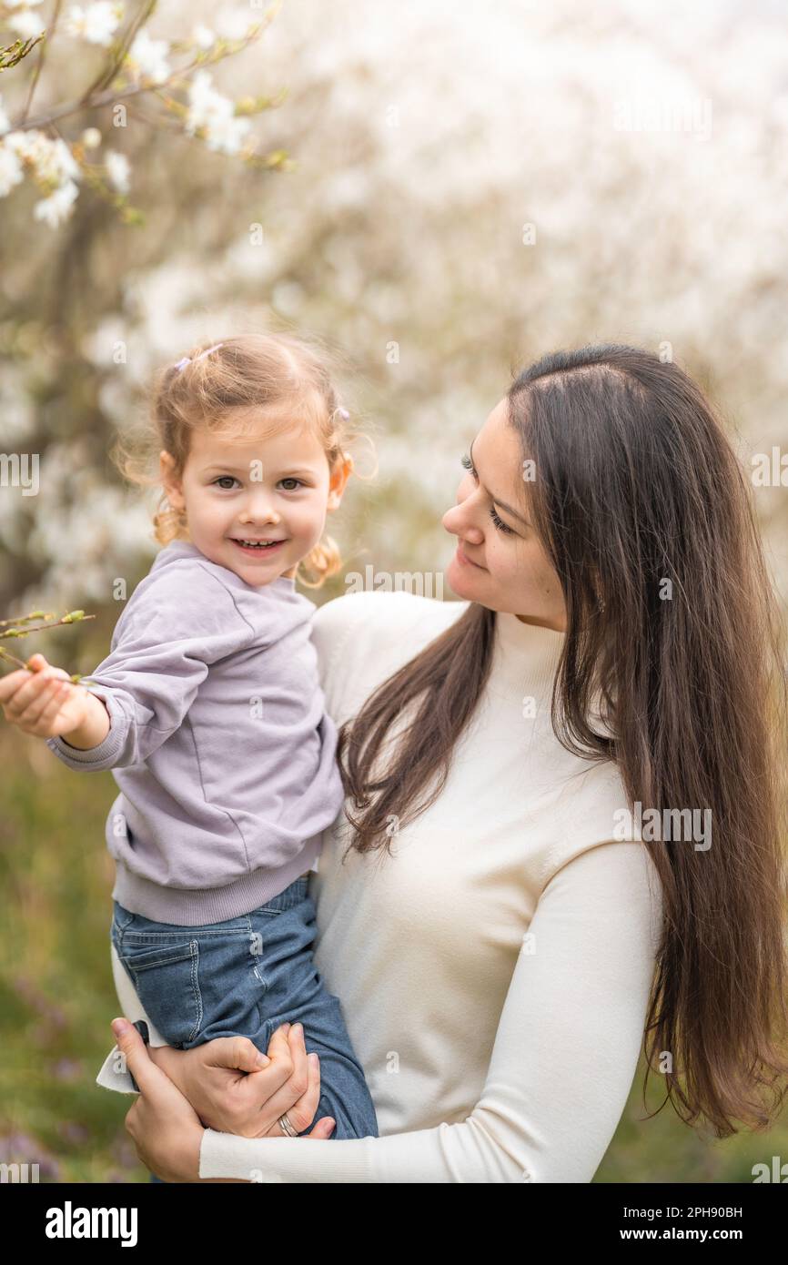 Young mother and her cute daughter having a fun in spring time park ...