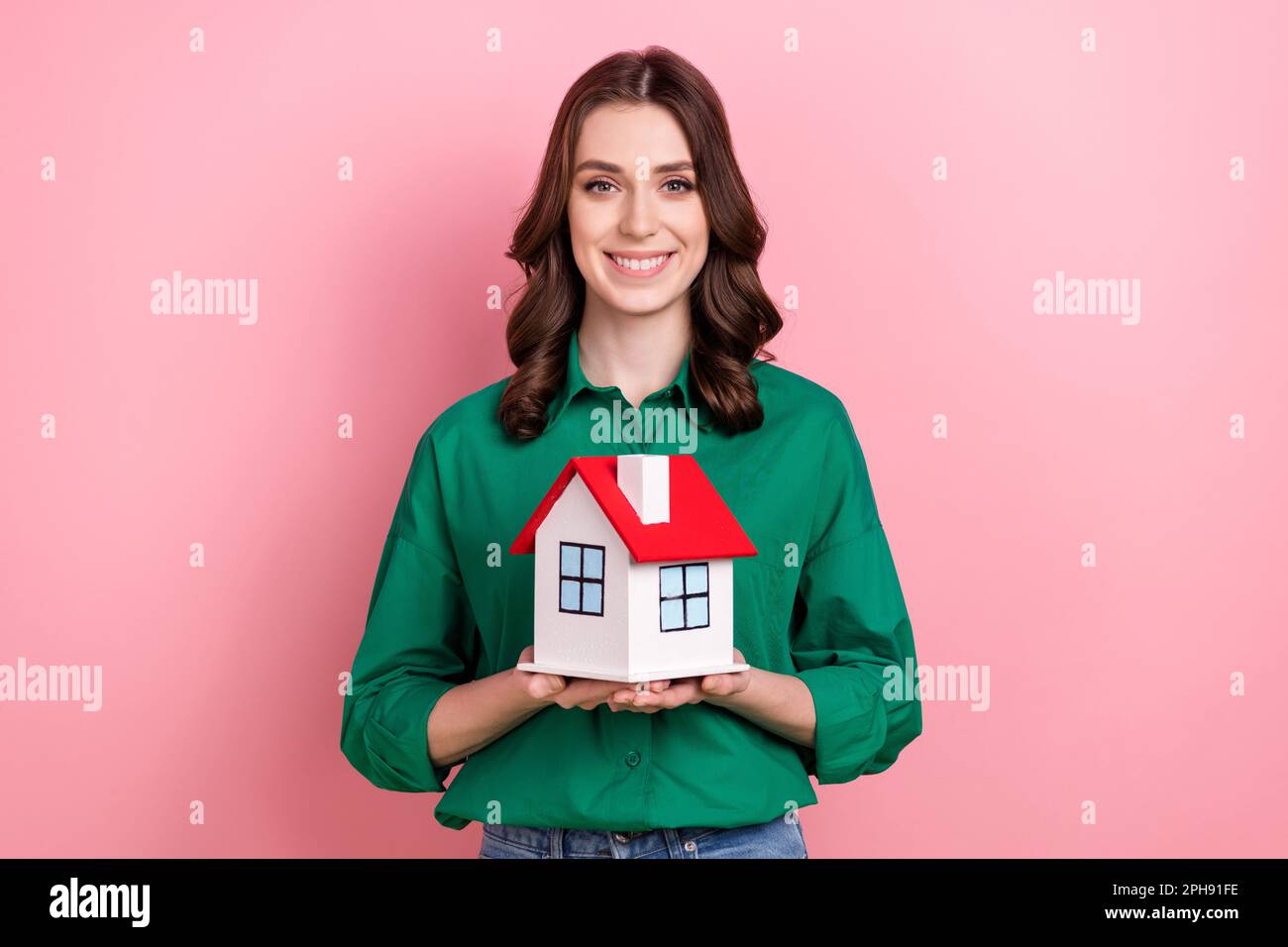 Photo of sweet charming lady dressed green blouse holding small red roof house isolated pink color background Stock Photo