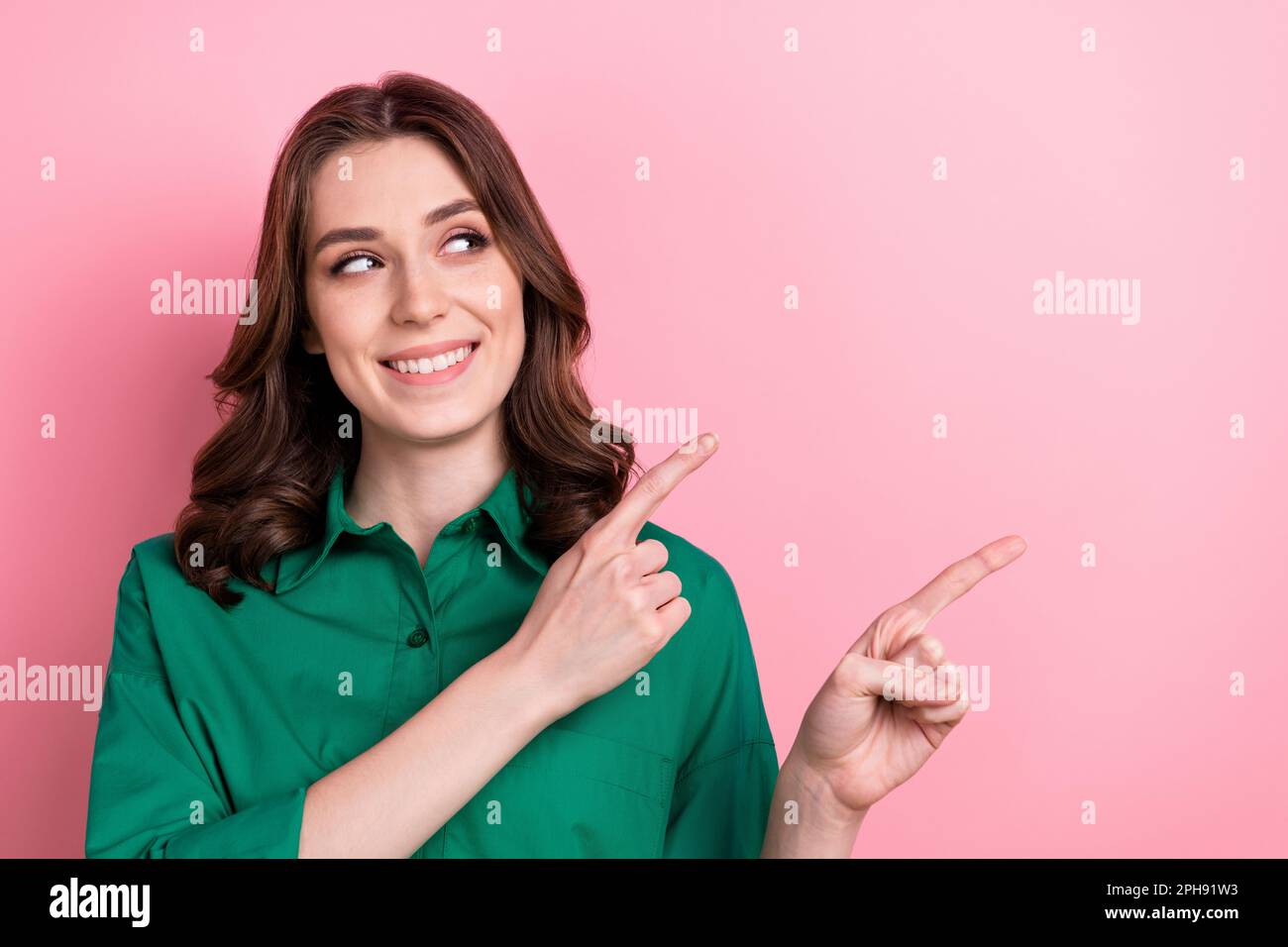 Portrait of charming positive agent girl toothy smile look direct fingers empty space isolated on pink color background Stock Photo