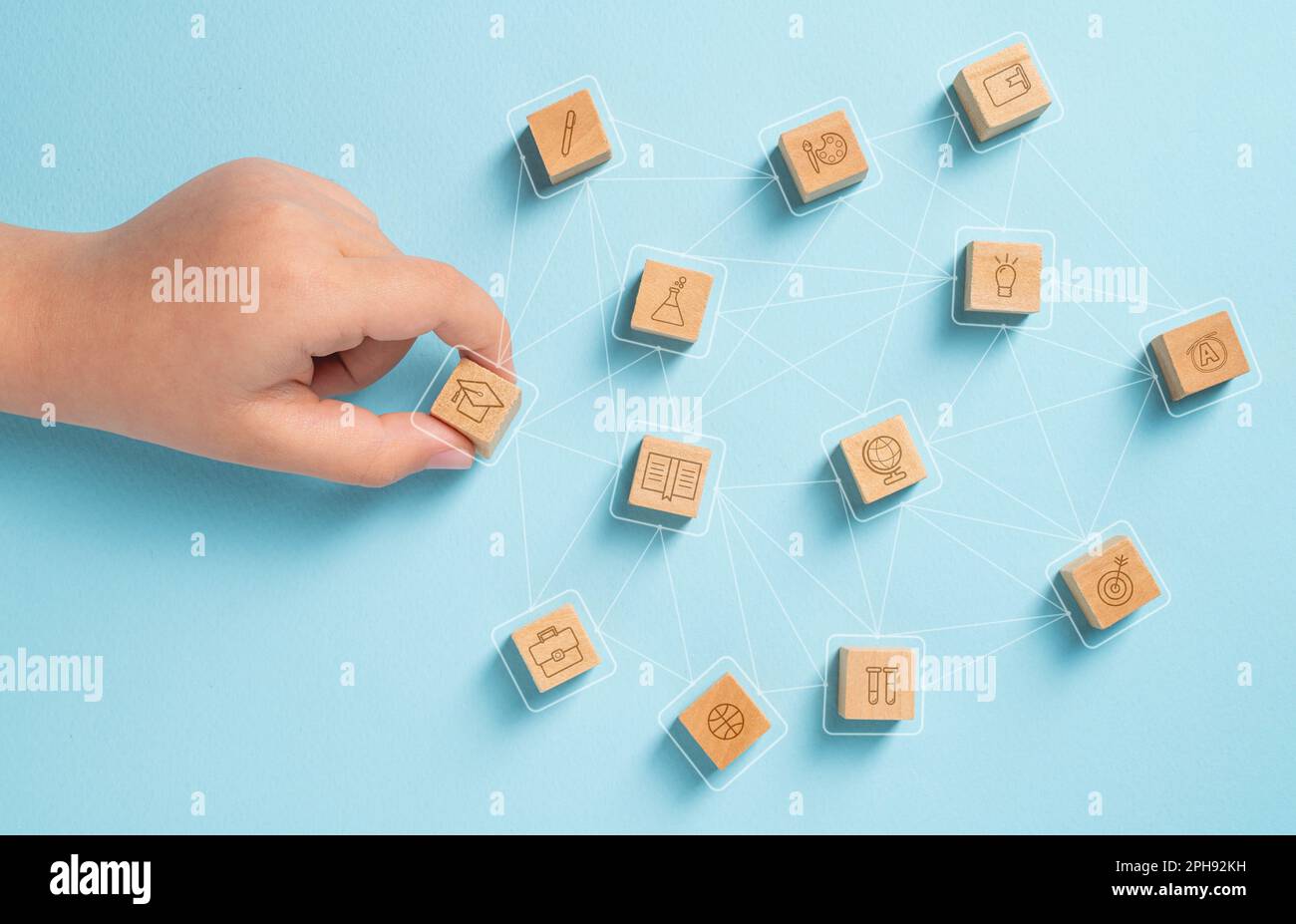 Student organizing wooden cubes with education icons. Education concept Stock Photo
