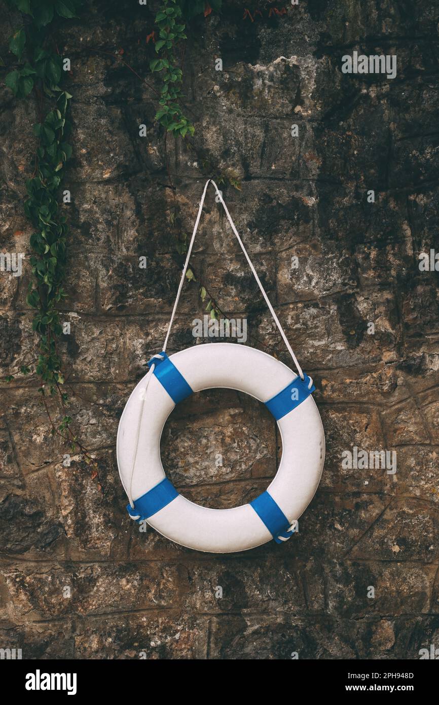 Lifebuoy, life saving ring on stone wall with creeping ivy, toned image Stock Photo