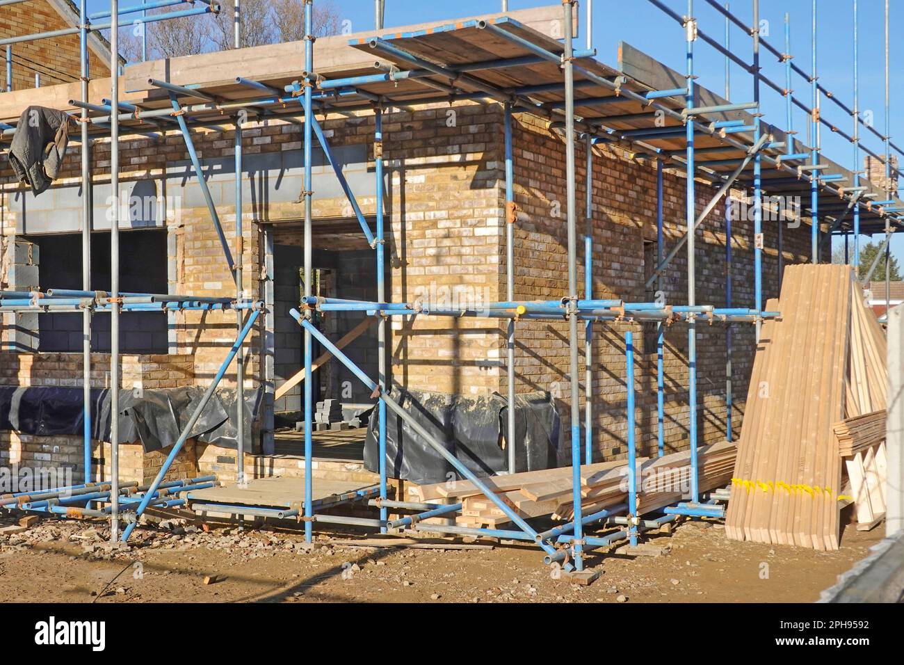 House building construction health & safety via independent access scaffolding with tubular scaffold diagonal bracing toe boards body hand rails in UK Stock Photo