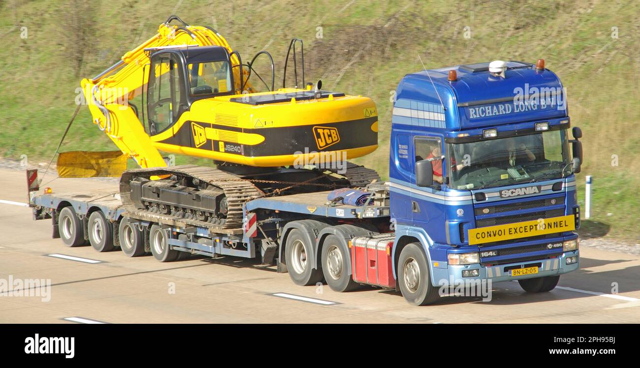 Netherlands NL country code on Scania 164L 480 lorry truck & low loader trailer JCB JS240 excavator wide load CONVOI EXCEPTIONNEL on UK motorway road Stock Photo