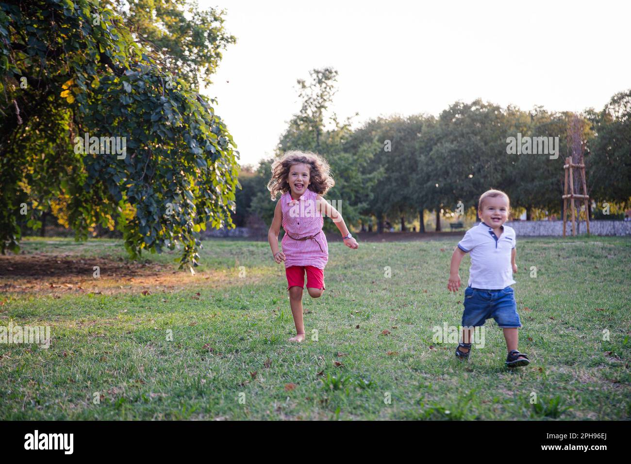Brother and sister playing together in the park outdoors on a summer ...