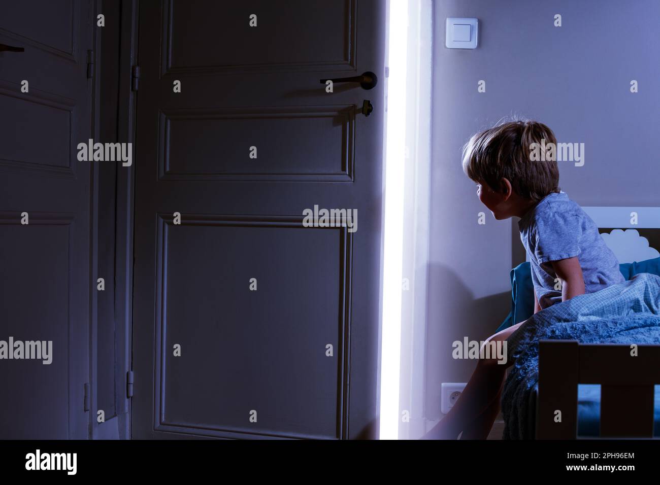 Boy in bedroom look at light coming from the open door Stock Photo Alamy